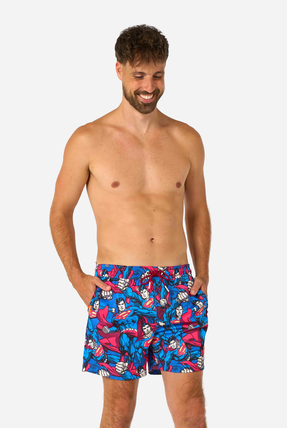 Man wearing a Men's Superman-themed swim shorts featuring a bold comic book design with multiple action poses of the Man of Steel. Perfect for superhero fans looking to make a splash. Close-up of his middle.