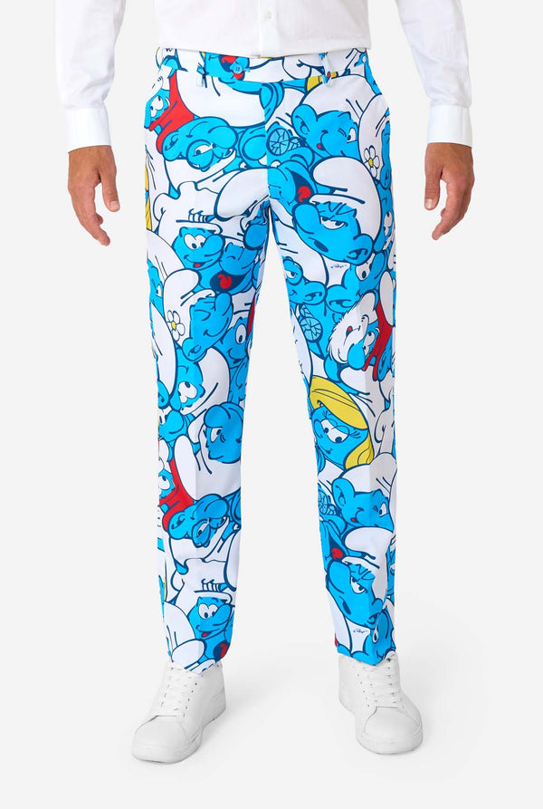 Man wearing a colorful Smurfs men's suit with an all-over cartoon print in blue, white, red, and yellow, including a matching tie and white shirt, standing against a plain background. Pants close up.