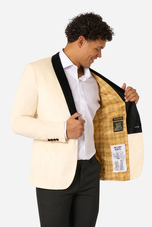 Man wearing a cream blazer with a plaid lining, white shirt, and black pants on a light background.