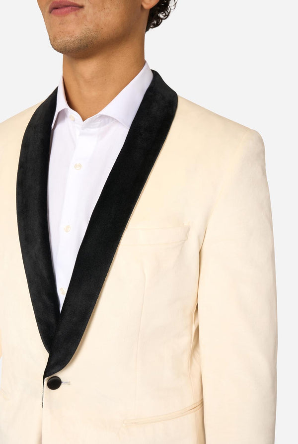 Cream-colored blazer with black lapels worn by a person on a light background. Chest close up. 