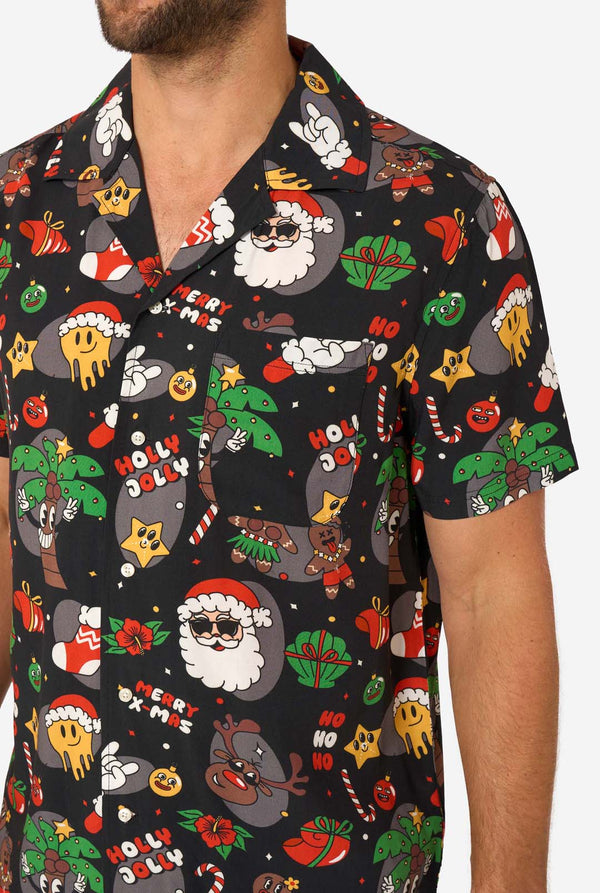 Man wearing a black Christmas-themed shirt with colorful graphics on a white background