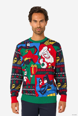 Man wearing a colorful knitted Christmas sweater featuring comic-style Batman graphics with festive holiday details.