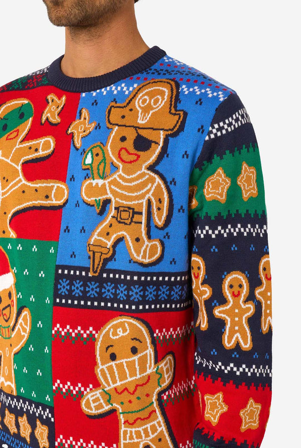 Close-up of the knitted Christmas sweater’s front, showing gingerbread characters dressed as a pirate, ninja, and Santa.