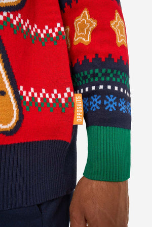 Close-up of the knitted Christmas sweater hem with an orange “Opposuits” label and green ribbed cuff.