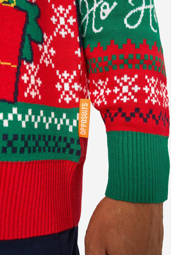 Close-up of the knitted Christmas sweater’s hem showing snowflake patterns, green cuffs, and an orange “Opposuits” label.
