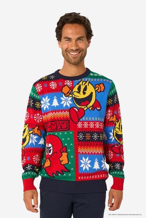 Smiling man wearing a colorful knitted Christmas sweater featuring Pac-Man and a red ghost with festive snowflake patterns.