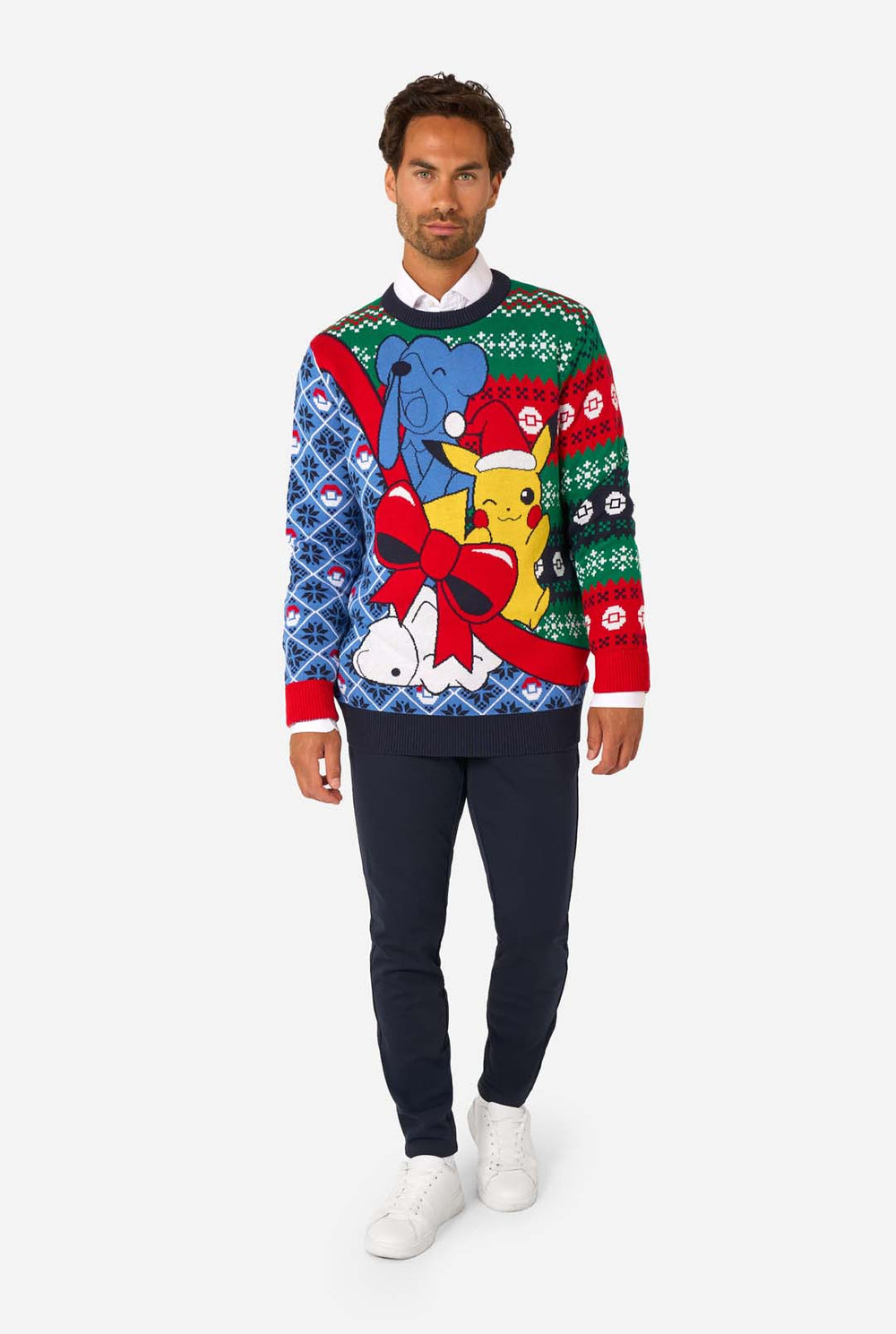 Smiling man wearing a colorful knitted Christmas sweater featuring Pikachu in a Santa hat with a red bow and festive patterns.