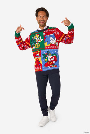 Smiling man pointing at his festive Sonic-themed knitted Christmas sweater.