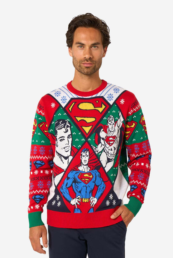Man wearing a colorful knitted Christmas sweater featuring multiple Superman designs and the iconic “S” logo.