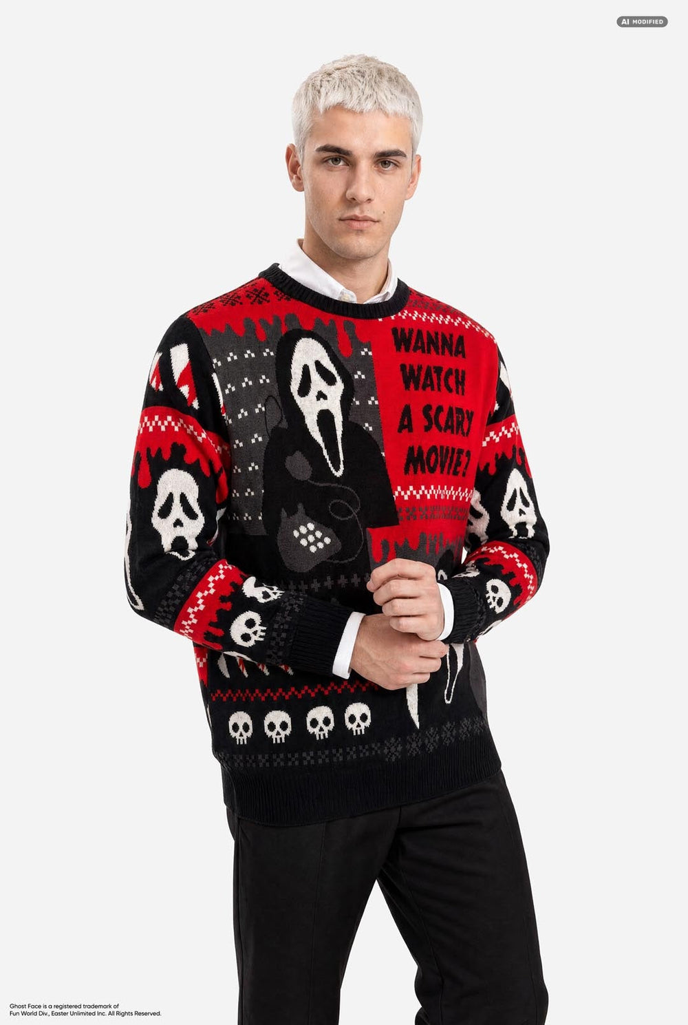 A male model with platinum blonde hair wearing a black and red Halloween-themed knit sweater with Ghostface and skull patterns, paired with black pants, against a light gray background.