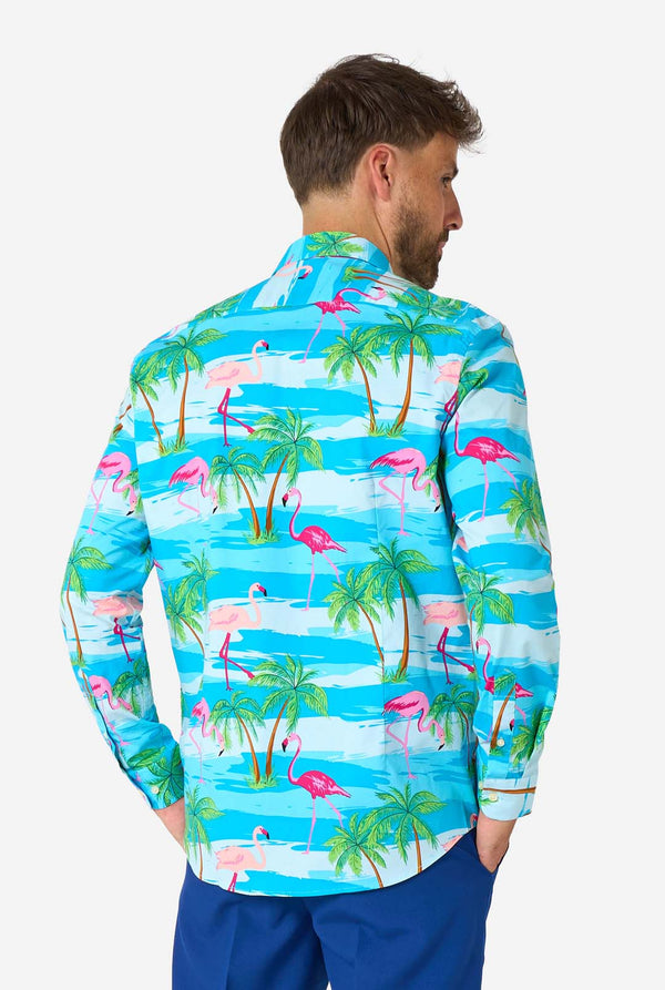 Man wearing a colorful shirt with flamingo and palm tree pattern on a white background, view from the back.