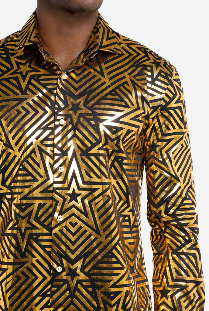 This image features a men’s shirt from OppoSuits with a vibrant gold and black geometric star print pattern. The shirt has a reflective finish that highlights the intricate star and line designs, creating a dynamic and stylish look. Perfect for those who want to stand out, this shirt is both bold and fashionable, ideal for parties, holiday celebrations, or nightlife. The model wears it paired with black pants. Chest close up.