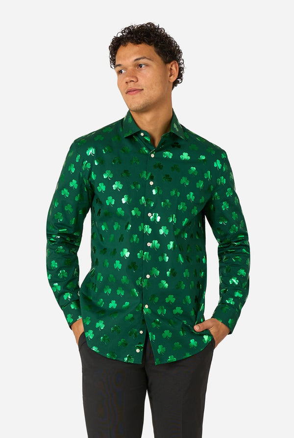 Man wearing a green clover-patterned St. Patrick's Day shirt on a light background