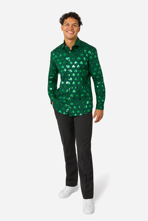 Man wearing a green clover-patterned St. Patrick's Day shirt on a light background. Full body image.