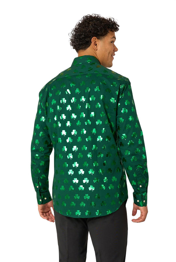 Man wearing a green clover-patterned St. Patrick's Day shirt on a light background. View from the back.