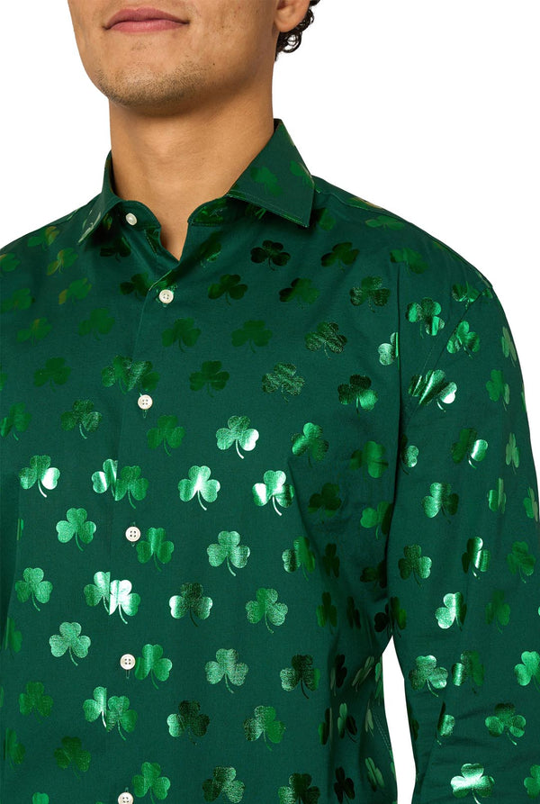 Man wearing a green clover-patterned St. Patrick's Day shirt on a light background. Chest close up.