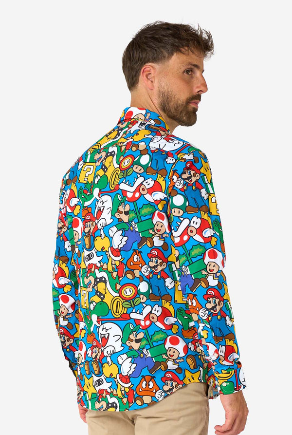 Man wearing a colorful shirt with Super Mario characters pattern on a white background. View from the side.