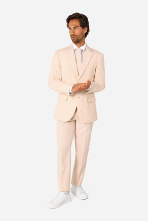 Image of a man wearing a sand colored beige suit and a white shirt. Full body image.