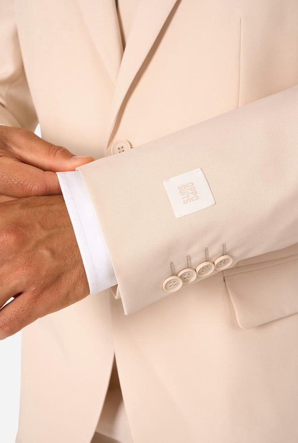 Image of a man wearing a sand colored beige suit and a white shirt. Sleeve close-up.