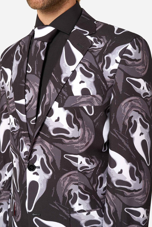 A close-up of a men's suit jacket featuring a bold black, white, and gray Ghostface-style mask pattern, styled with a black dress shirt and black tie.
