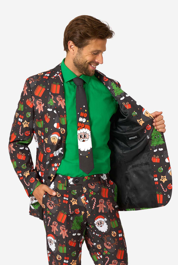A man poses in a black background colored christmas suit decorated with festive holiday imagery like reindeer, snowflakes, and gift boxes. Showing the inside of his jacket