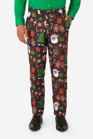 A man poses in a black background colored christmas suit decorated with festive holiday imagery like reindeer, snowflakes, and gift boxes. Close up of the pants