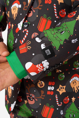 A man poses in a black background colored christmas suit decorated with festive holiday imagery like reindeer, snowflakes, and gift boxes. Close up of the sleeves