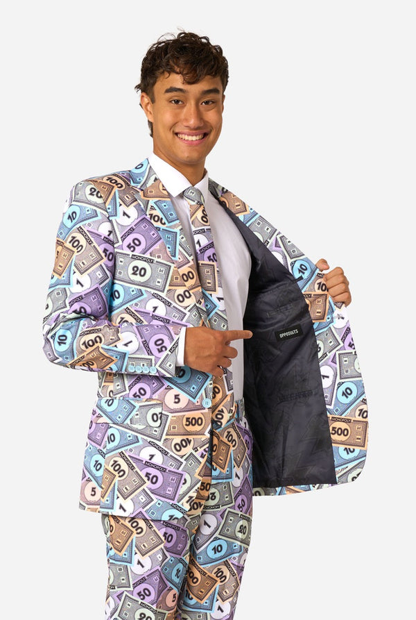 Image of a man wearing a men's suit with an all over print from Monopoly money. He is also wearing a white men's shirt. Holding one side of the jacket open.