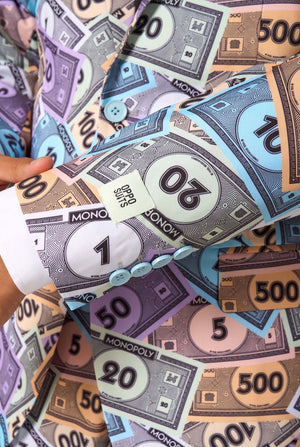 Image of a man wearing a men's suit with an all over print from Monopoly money. He is also wearing a white men's shirt. Sleeve close-up.