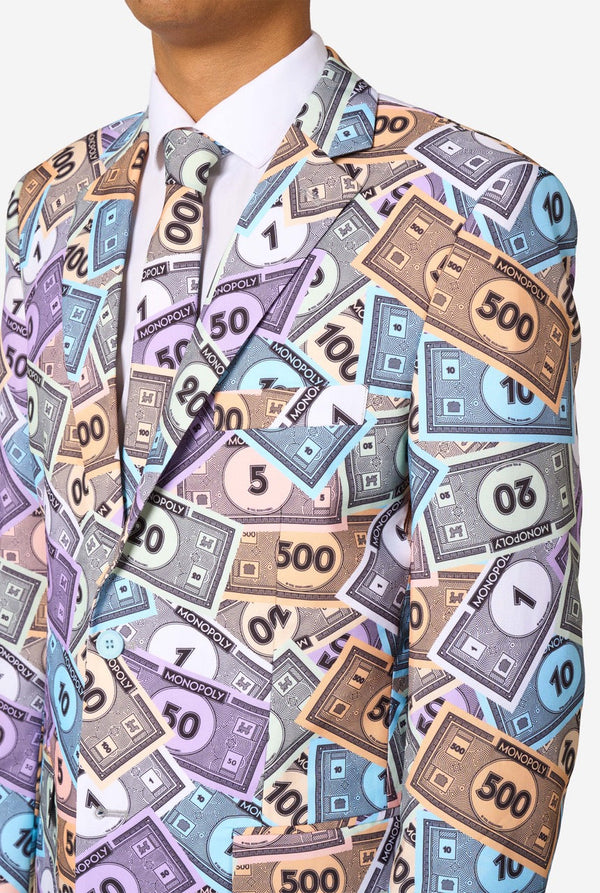 Image of a man wearing a men's suit with an all over print from Monopoly money. He is also wearing a white men's shirt. Chest close-up.