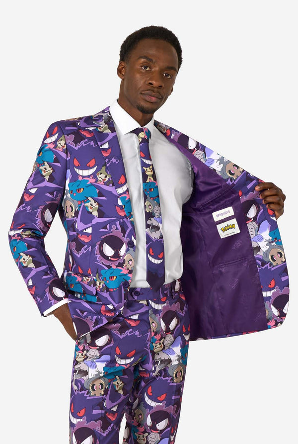 A man wearing a Ghost Pokemon themed suit with a Ghost Pokemon themed tie and a white shirt on a white background. Holding his jacket open