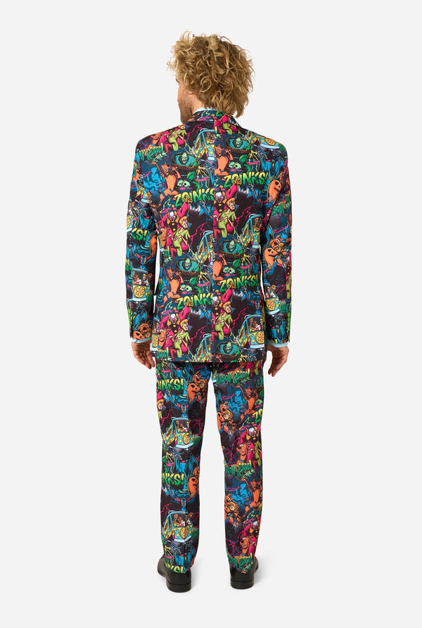 View from the back of a man wearing a vibrant, multicolored Scooby-Doo print suit jacket and matching tie. The pattern features various Scooby-Doo characters in bright neon colors on a dark background, styled with a light blue dress shirt.