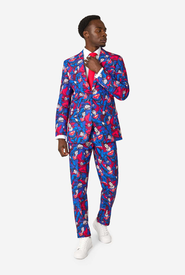 A man wearing a Superman themed suit with a red tie and a white shirt on a white background. Full body image
