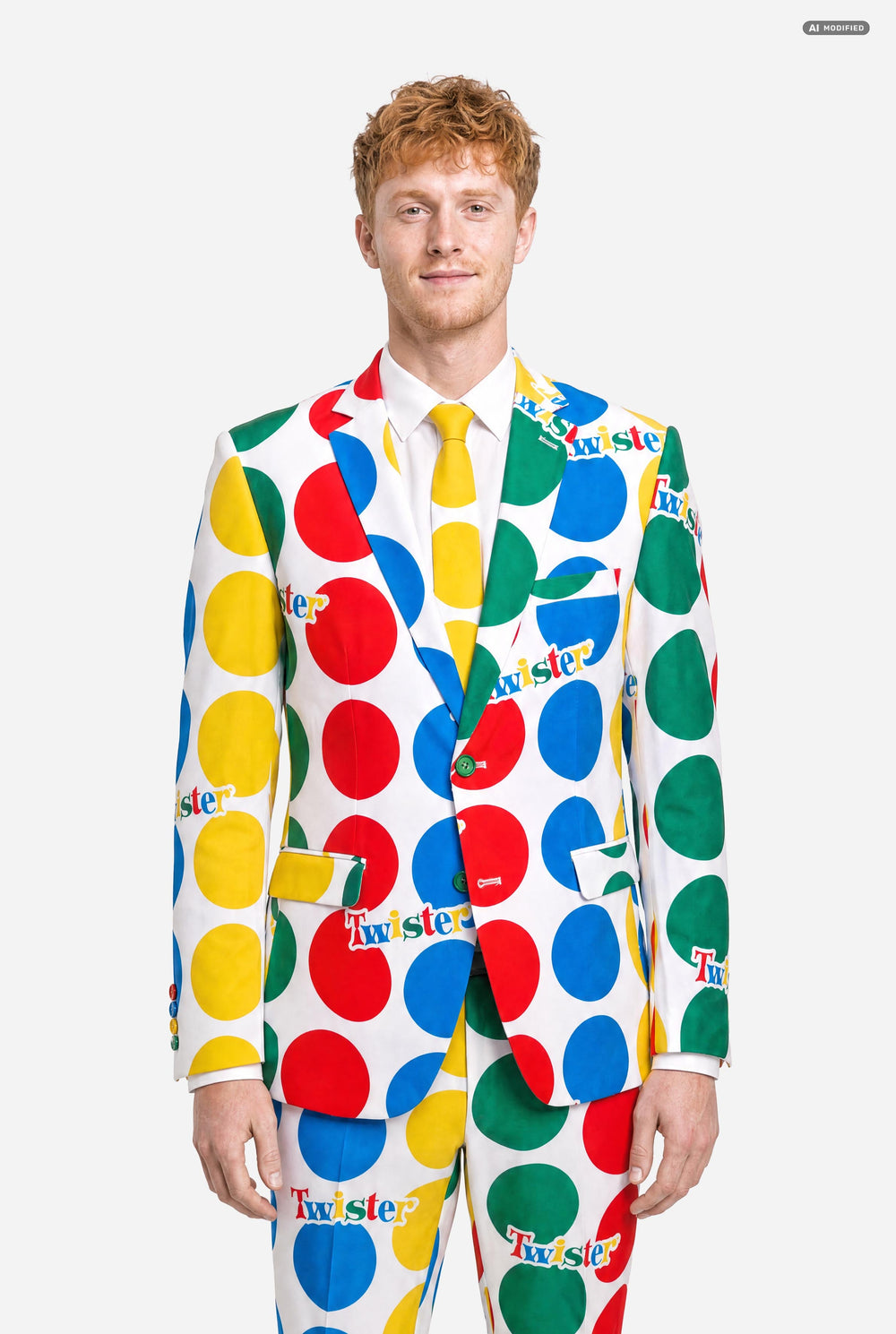 A man wearing a white suit with large multicolored polka dots and the Twister logo, resembling a Twister mat paired with a white and yellow tie, against a light gray studio background.