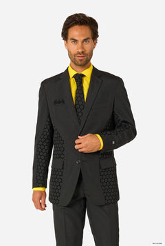 Man wearing a black Batman suit with geometric patterns and a yellow shirt on a white background