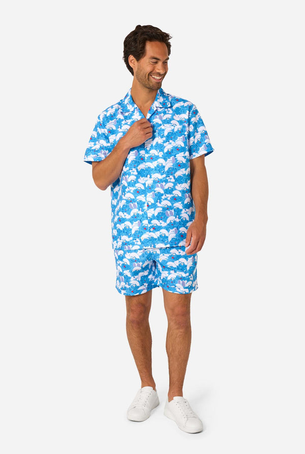 Man wearing a blue and white Smurfs patterned shirt and shorts on a light background.
