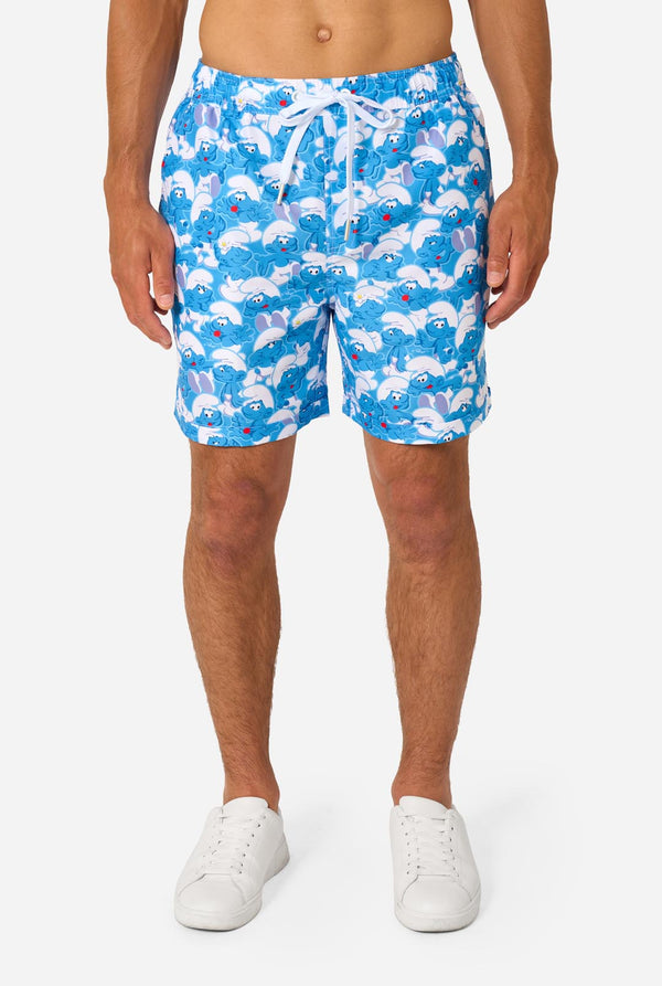 Man wearing a blue and white Smurfs patterned shirt and shorts on a light background. Close up of shorts.