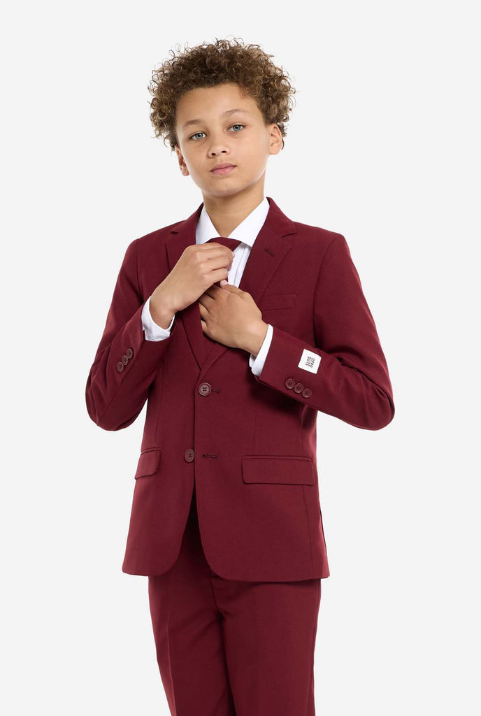 Teen wearing formal burgundy red suit, kid holding tie