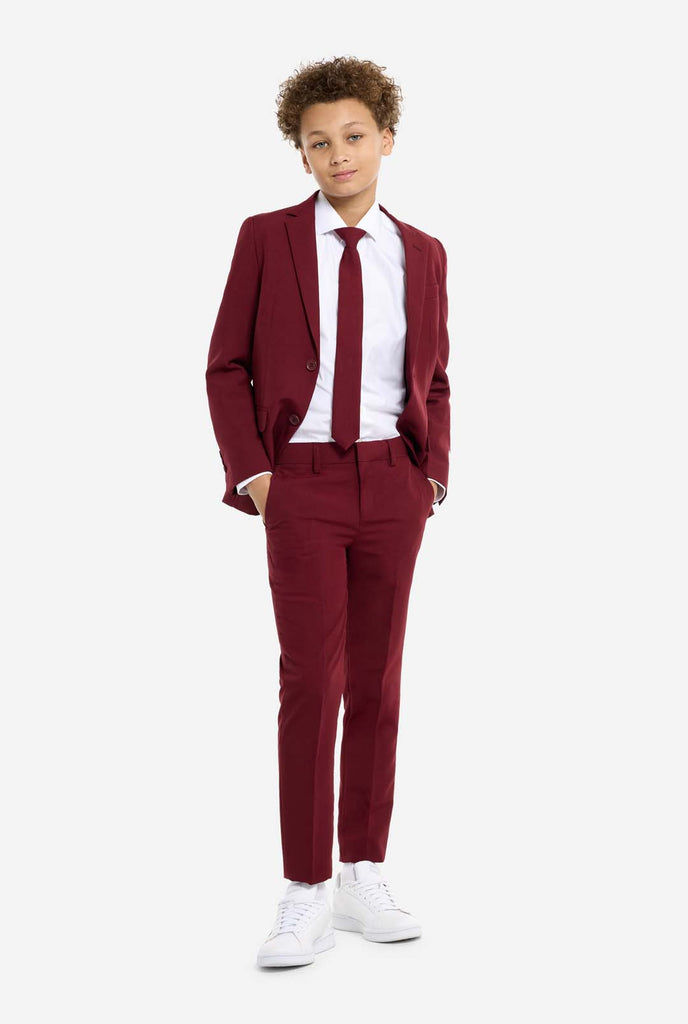 Teen wearing formal burgundy red suit, standing with hands in pockets