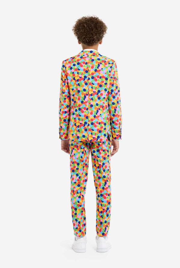 In this image, a kid is wearing a colorful, polka-dotted suit. The suit has a bright pattern with circles in various colors including orange, yellow, pink, green, blue, and red, arranged in a confetti-like style., view from the back