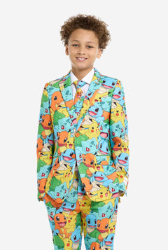 Teen wearing formal multi color suit with all-over Pokemon print. The suit contains the characters Pikachu, Bulbasaur, Charmander and Squirtle. Kid stands with hands in pockets.