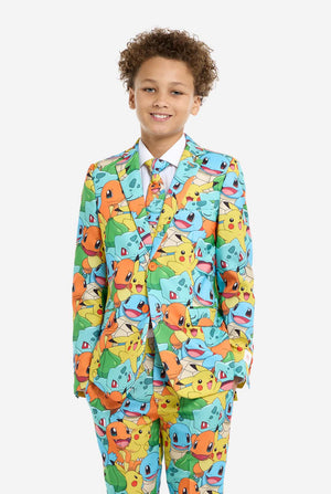 Teen wearing formal multi color suit with all-over Pokemon print. The suit contains the characters Pikachu, Bulbasaur, Charmander and Squirtle. Kid stands with hands in pockets.