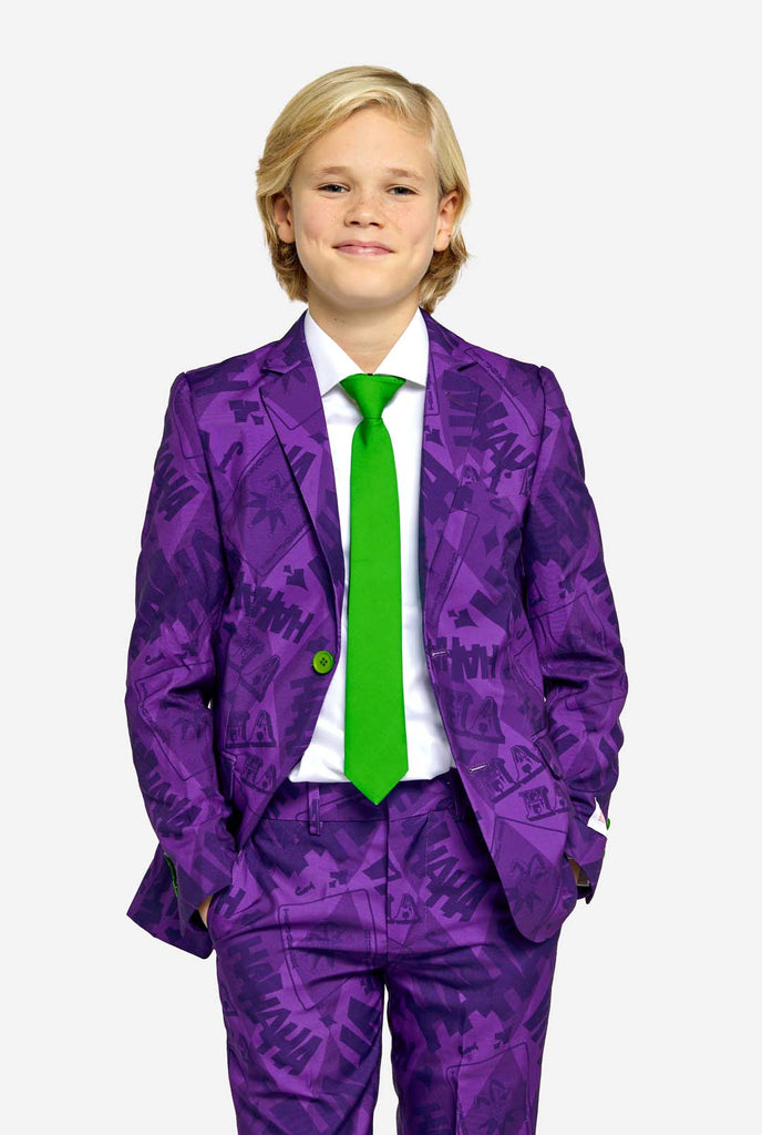 Teen wearing purple teen boys suit with a The Joker theme and green buttons. Further he is wearing a green tie and a white shirt. Hands in pockets of pants.