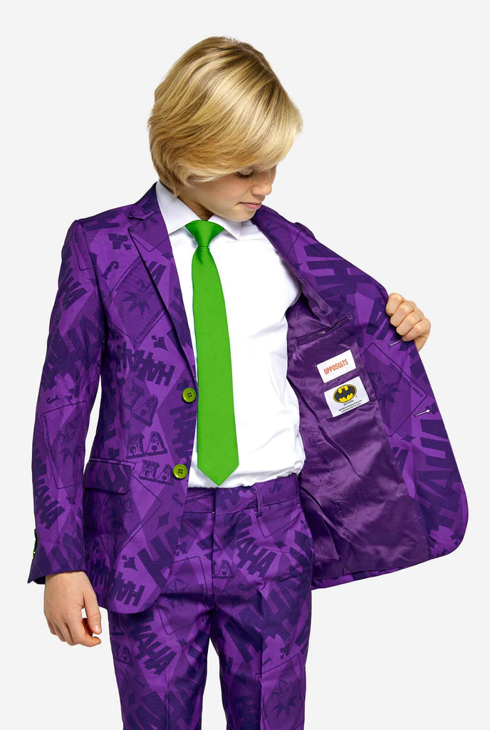 Teen wearing purple teen boys suit with a The Joker theme and green buttons. Further he is wearing a green tie and a white shirt. Showing the inside of the jacket on one side.