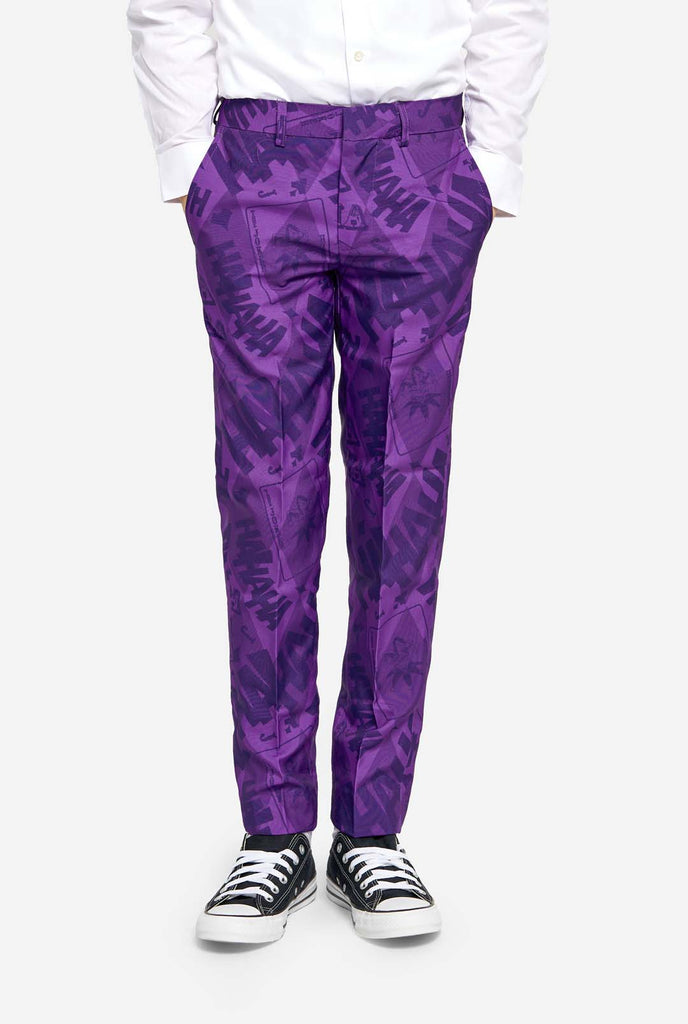 Teen wearing purple teen boys suit with a The Joker theme. Further he is wearing a white shirt and black and white sneakers. Hands in pockets of pants. Zoomed in on pants.