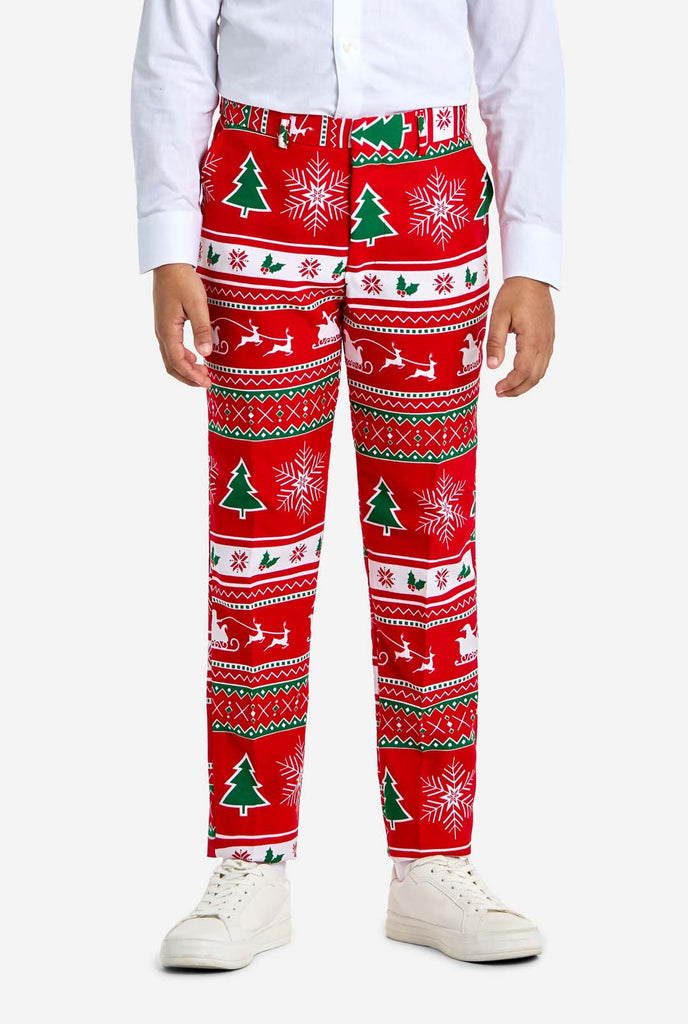 Teen wearing red Christmas suit with green and white Christmas icons, like Christmas tree, snowflakes, holly and sled with reindeers. Pants view.