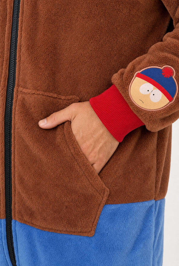 Close-up of the Stan onesie showing the brown fleece fabric, front pocket and character sleeve patch.