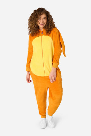 A woman modeling a plush animal onesie in bright orange and yellow, standing against a light gray studio background.