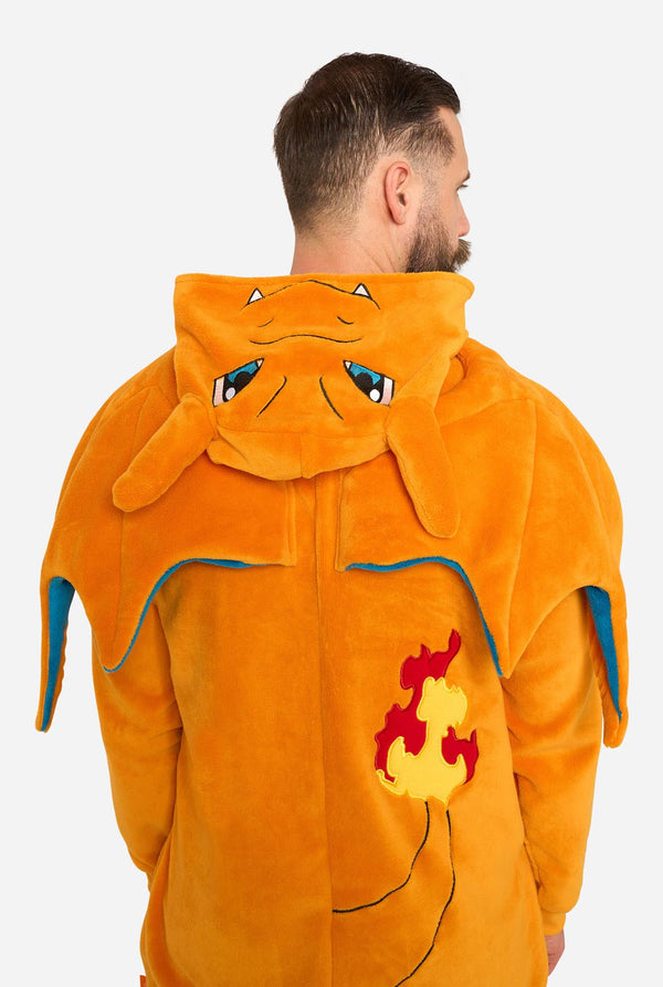 A man wearing a plush orange Charizard hooded onesie, shown from the back against a light gray studio background.