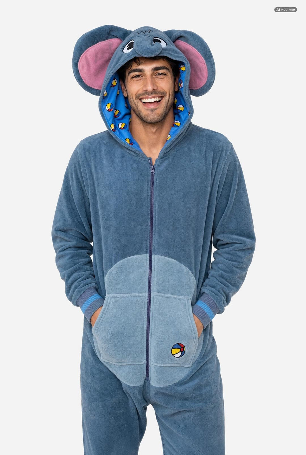 A man wearing a blue elephant onesie pajama with pink inner ears, a full front zipper, and a hood, standing against a light gray background.